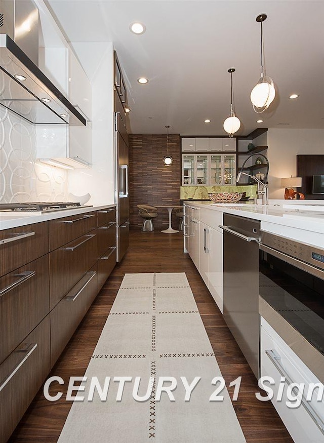 kitchen featuring wall chimney exhaust hood, appliances with stainless steel finishes, light countertops, and white cabinetry