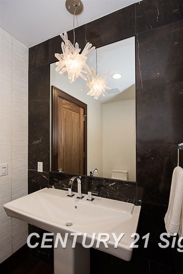 bathroom with a sink and tile walls