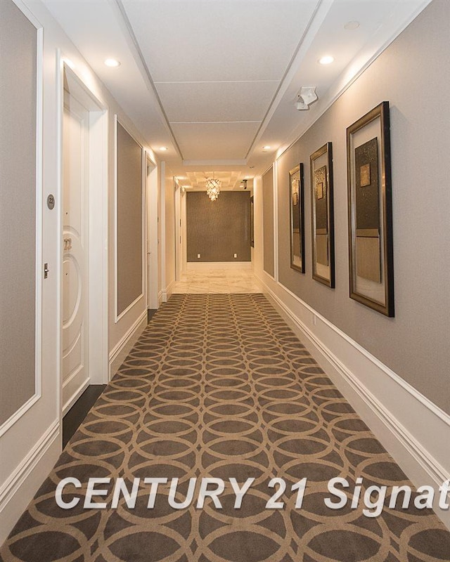 hall with baseboards, dark carpet, and recessed lighting