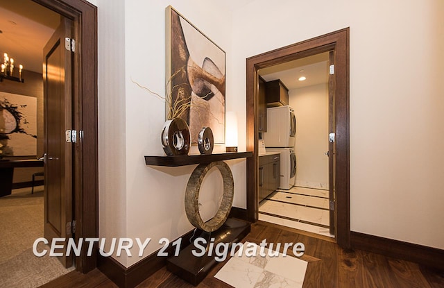 hallway with stacked washer / drying machine, baseboards, and wood finished floors