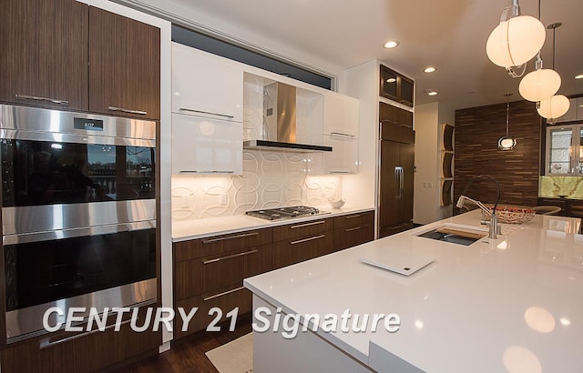 kitchen with wall chimney range hood, modern cabinets, appliances with stainless steel finishes, and light countertops