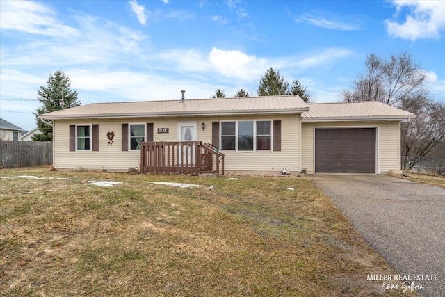 ranch-style home featuring an attached garage, a front yard, metal roof, fence, and driveway