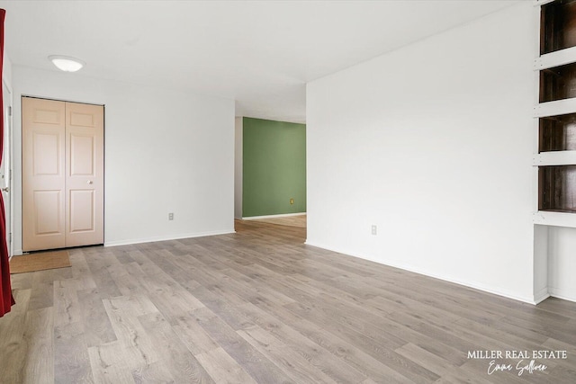 spare room with baseboards and wood finished floors