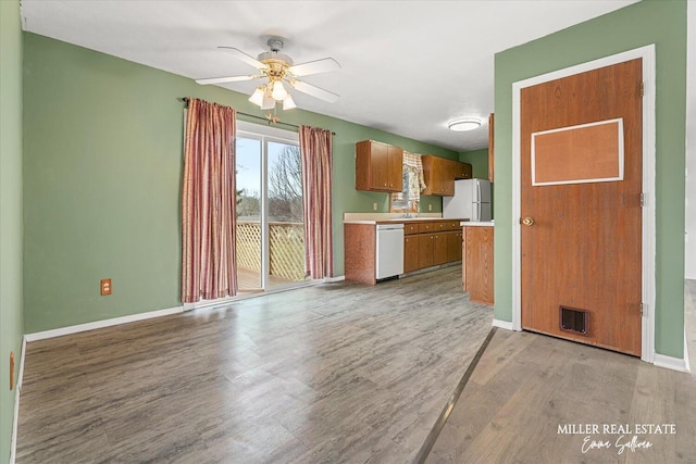 kitchen featuring white appliances, visible vents, baseboards, light countertops, and light wood finished floors