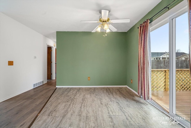 empty room with visible vents, ceiling fan, baseboards, and wood finished floors