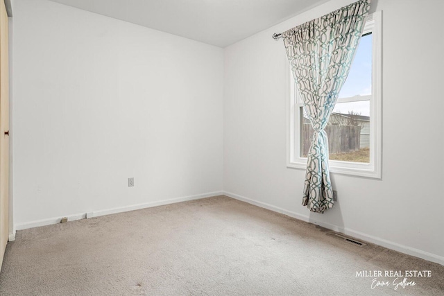 spare room with carpet, visible vents, and baseboards