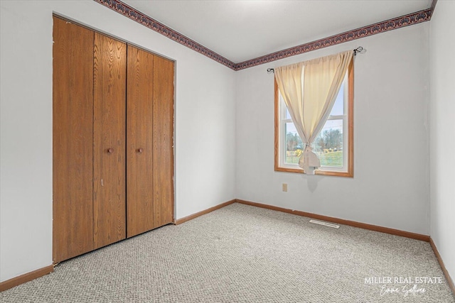 unfurnished bedroom with baseboards, a closet, and light colored carpet