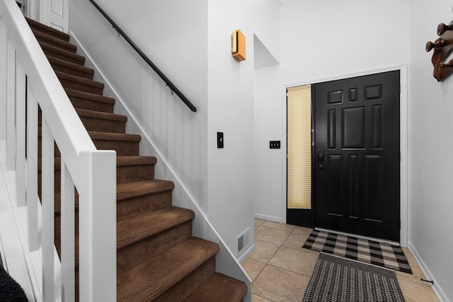 foyer entrance with light tile patterned flooring, stairway, and visible vents