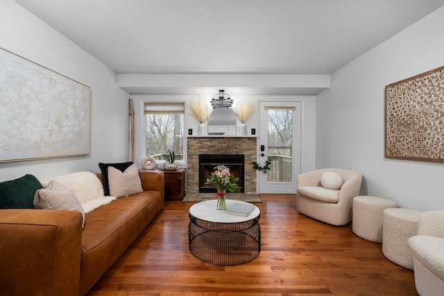 living room featuring a stone fireplace and wood finished floors