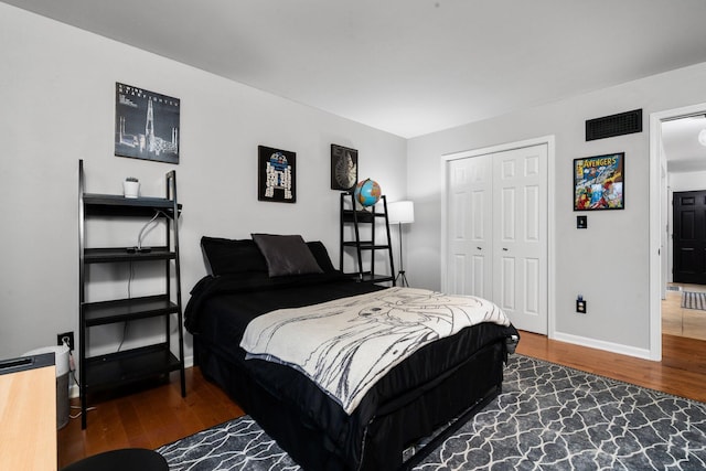 bedroom with a closet, baseboards, visible vents, and dark wood finished floors
