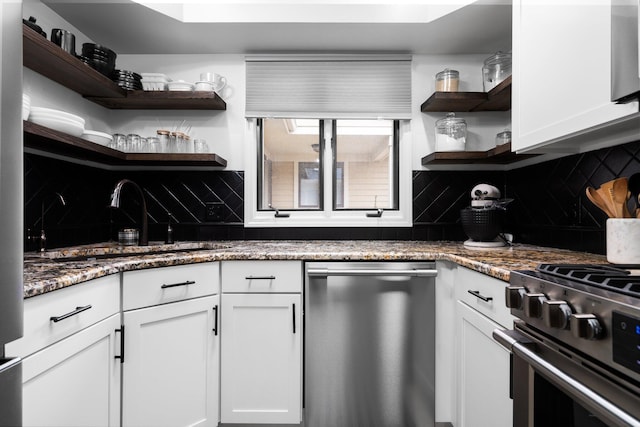 kitchen with open shelves, white cabinetry, dark stone counters, appliances with stainless steel finishes, and decorative backsplash