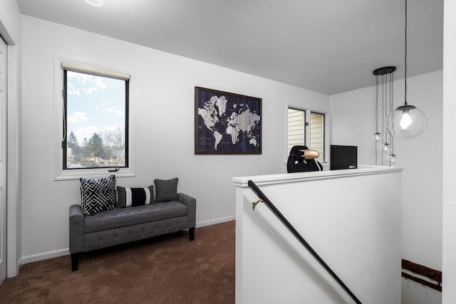 interior space featuring dark colored carpet, baseboards, and an upstairs landing