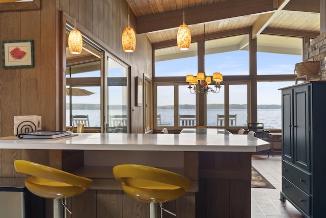 6863 Crystal Dr, Beulah, MI 49617 - kitchen featuring a water view, a chandelier, wooden ceiling, wood walls, and hanging light fixtures