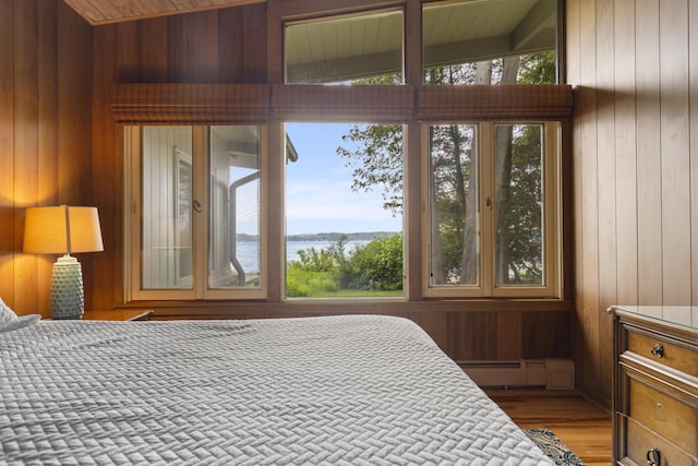 6863 Crystal Dr, Beulah, MI 49617 - bedroom featuring multiple windows, wooden walls, baseboard heating, a water view, and light wood-style flooring