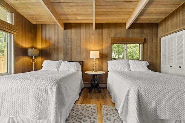 6863 Crystal Dr, Beulah, MI 49617 - bedroom featuring a wooden ceiling with exposed beams, wooden walls, wood finished floors, baseboard heating, and a closet
