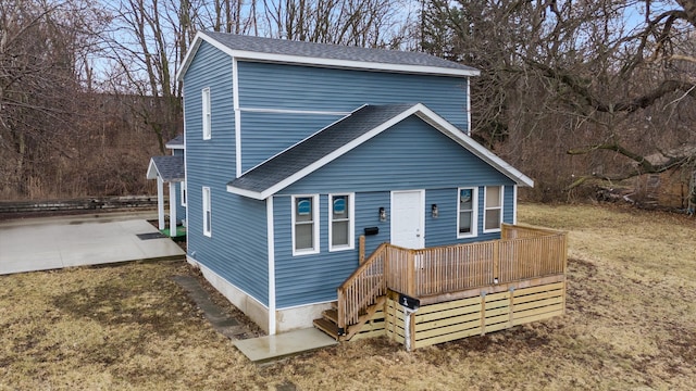 view of front of property with a patio, roof with shingles, and a wooden deck