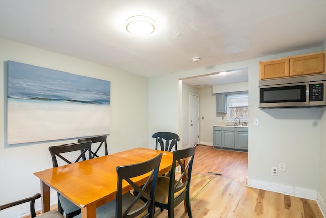 dining space featuring light wood-type flooring, visible vents, and baseboards