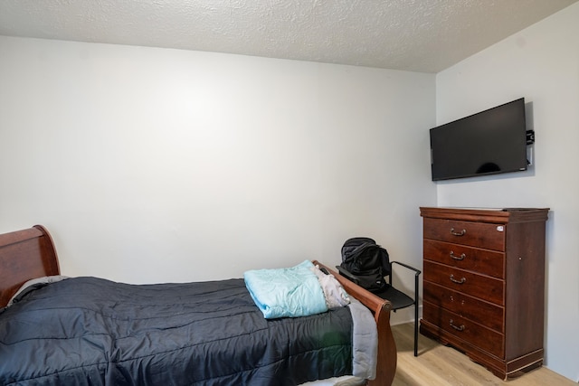 bedroom with light wood-style floors and a textured ceiling