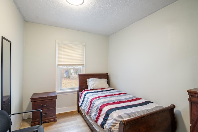 bedroom with a textured ceiling, wood finished floors, and baseboards