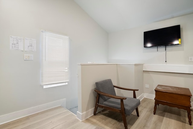 living area featuring vaulted ceiling, wood finished floors, and baseboards