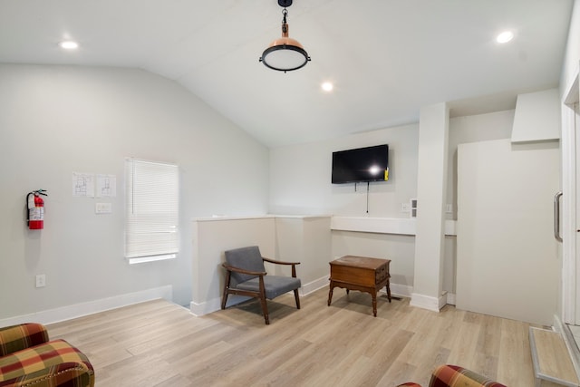 living area featuring lofted ceiling, light wood finished floors, and baseboards