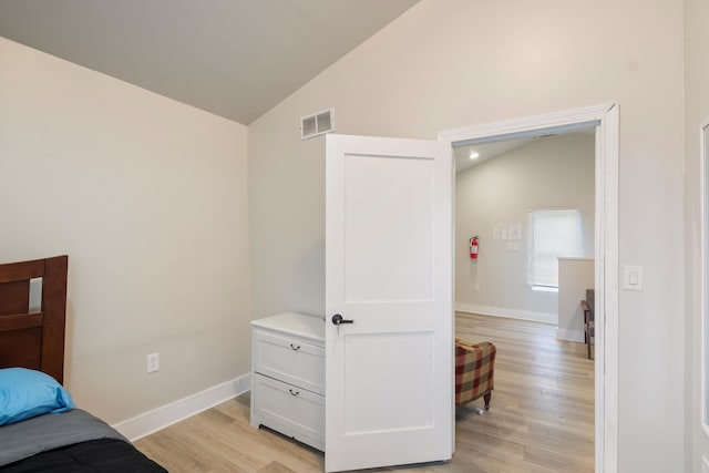 bedroom featuring lofted ceiling, light wood-style flooring, visible vents, and baseboards