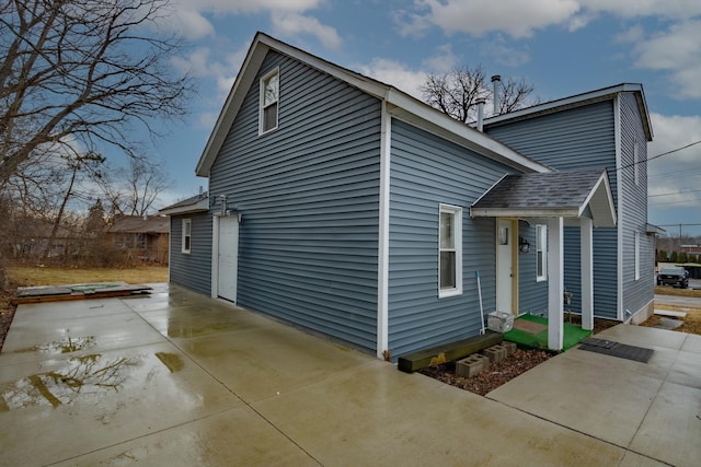 view of property exterior featuring concrete driveway and roof with shingles