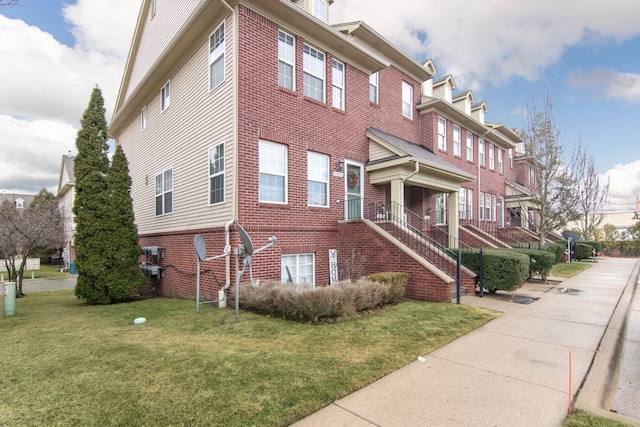 view of side of home with a yard, a residential view, stairway, and brick siding