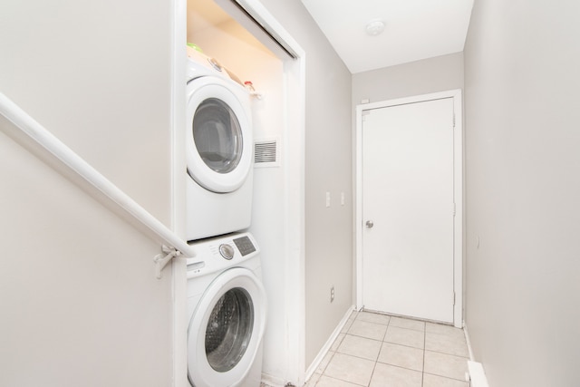 washroom featuring stacked washer / dryer, laundry area, light tile patterned flooring, and baseboards