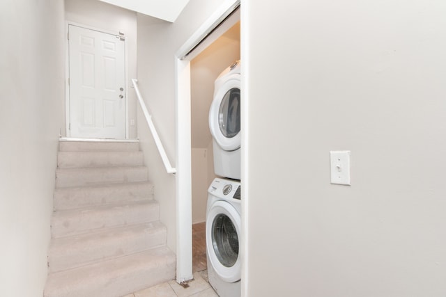 clothes washing area with stacked washing maching and dryer and tile patterned flooring