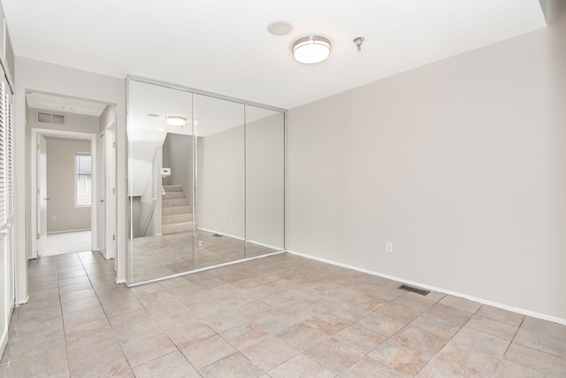 unfurnished bedroom with a closet, visible vents, and baseboards