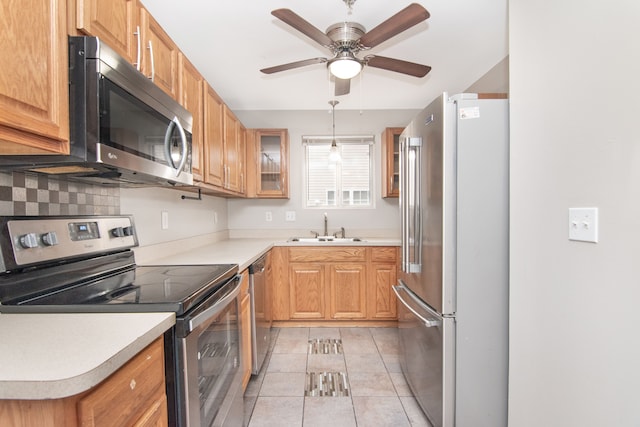 kitchen with light tile patterned floors, stainless steel appliances, light countertops, decorative backsplash, and a sink