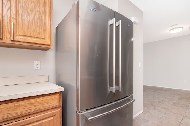 kitchen featuring light countertops, high quality fridge, baseboards, and light brown cabinetry