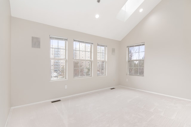 unfurnished room with light carpet, a skylight, baseboards, and visible vents