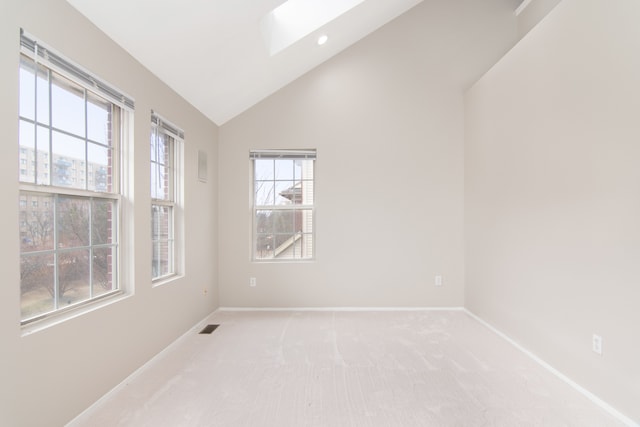 spare room featuring recessed lighting, light colored carpet, visible vents, vaulted ceiling with skylight, and baseboards