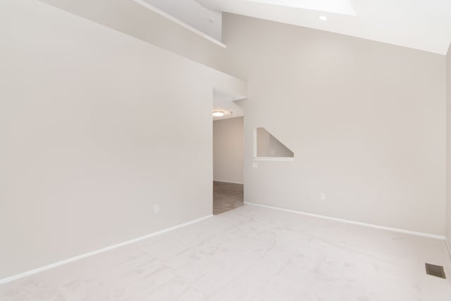 additional living space with light carpet, vaulted ceiling, and baseboards