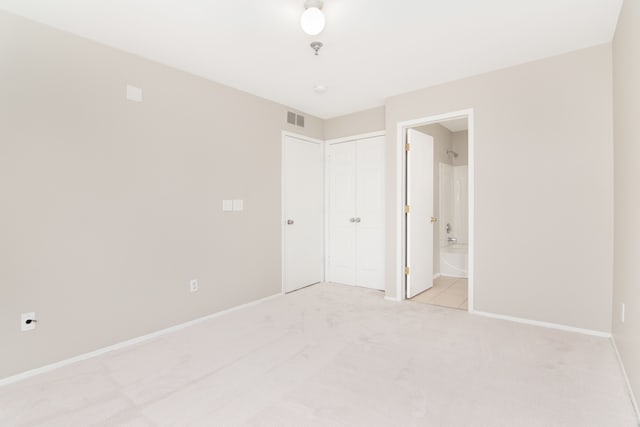 unfurnished bedroom with ensuite bathroom, baseboards, visible vents, and light colored carpet