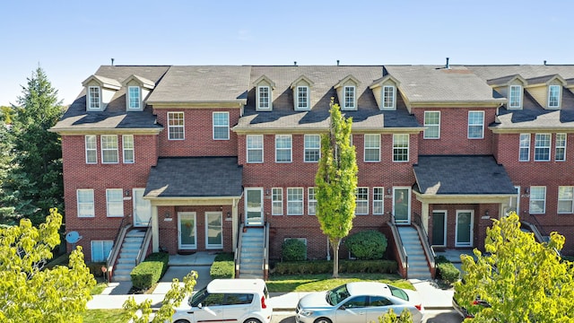 view of property featuring a residential view, brick siding, and stairway