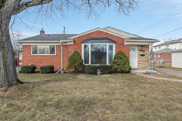 view of front of property featuring a front yard, brick siding, a chimney, and roof with shingles