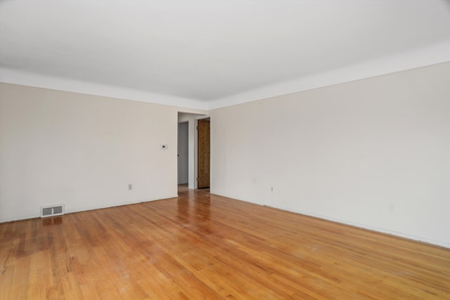 empty room with light wood-style floors and visible vents