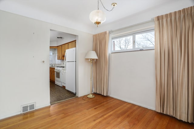 empty room with light wood-style floors and visible vents