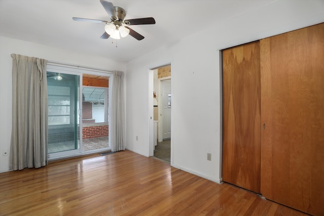 unfurnished bedroom featuring wood finished floors, visible vents, access to exterior, a ceiling fan, and baseboards