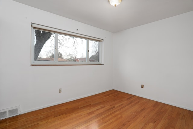 empty room featuring light wood-type flooring, visible vents, and baseboards