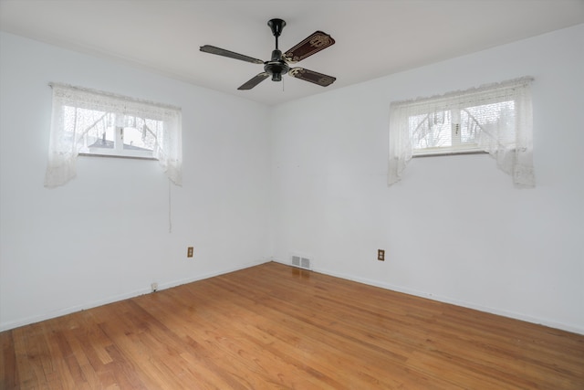 unfurnished room with light wood-style floors, baseboards, visible vents, and a ceiling fan