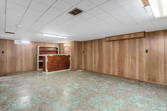 basement featuring wooden walls and tile patterned floors