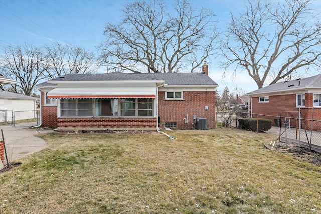 back of house featuring central AC unit, a lawn, and brick siding