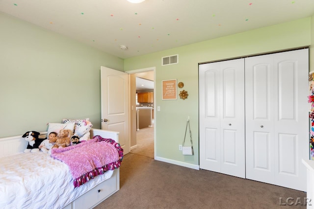 carpeted bedroom featuring a closet, visible vents, and baseboards