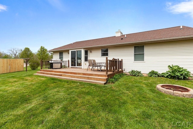 back of property featuring a yard, an outdoor fire pit, fence, and a deck