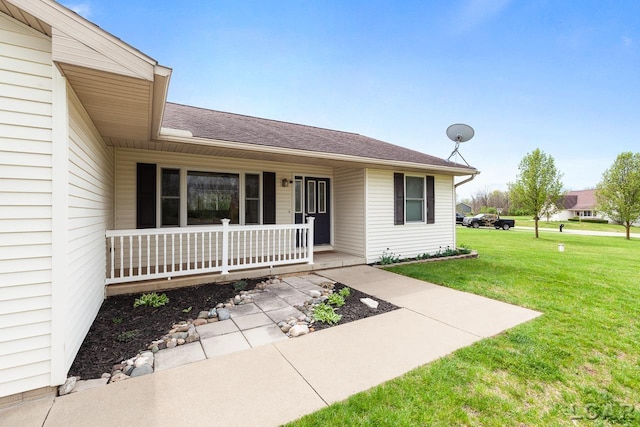 property entrance with covered porch, a shingled roof, and a yard