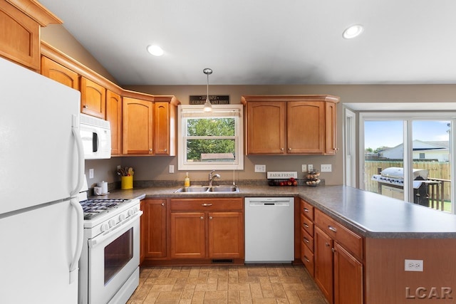 kitchen with white appliances, dark countertops, a peninsula, a sink, and recessed lighting